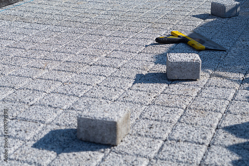Foto Pavement area with freshly laid paving stone tiles POV view with a few new remaining blocks and a large spatula