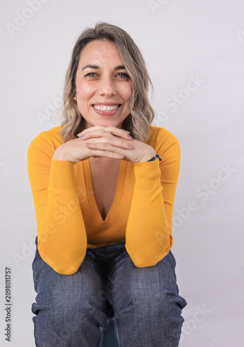 Smiling woman sitting by an open window at home, representing wellbeing, comfort, relaxation, positive lifestyle and enjoying a peaceful moment indoors.
