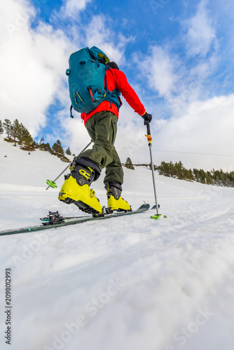 Man skiing on snowy mountain slope with blue sky