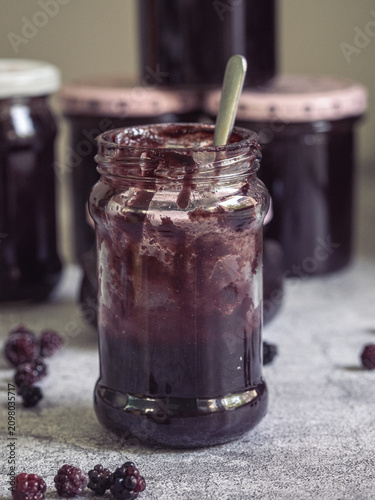 Blackberry jam in an open glass jar with spoon