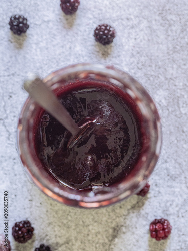 Blackberry jam in an open glass jar with spoon