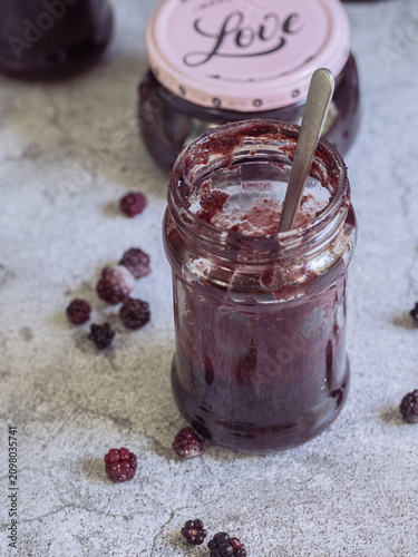 Blackberry jam in an open glass jar with spoon