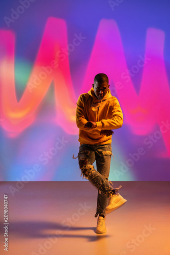 Black man urban dancer performing under colorful neon lights