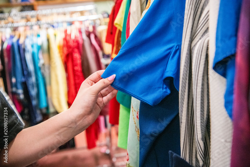 фотографія Close-up of a shopper selecting garments in a vintage clothing store