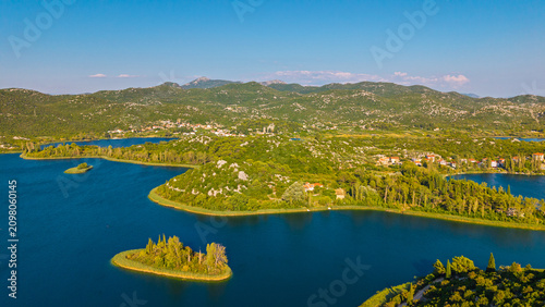 Aerial view of Bacina Lakes in Dalmatia, Croatia, featuring small islands, lush green hills, and blue water under a clear summer sky