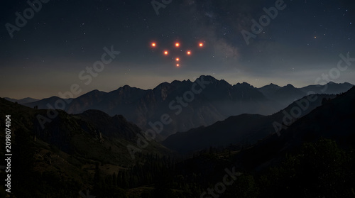 Mysterious orange lights hovering over mountain range at night