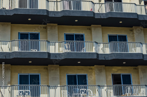 Картината върху платно Repeating balconies with white chairs and blue glass windows on a modern Medite