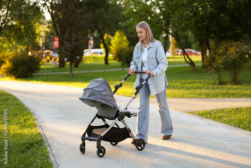 Fotografie Mother walking with her cute baby in stroller at park