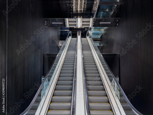Modern escalator in futuristic dark interior with black ribbed walls and symmetrical design. Contemporary architecture showing moving stairs in a business center or subway station