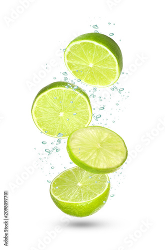 Limes and water drops in air against white background