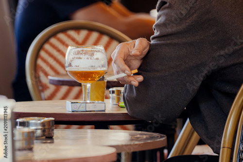 Man Smoking Cigarette and Drinking Beer at Outdoor Cafe