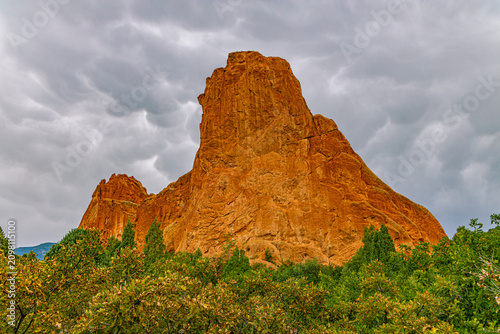 Konstfotografi The imposing, steep rock face of the Tower of Babel sandstone monolith towering over green trees under a moody, overcast stormy sky