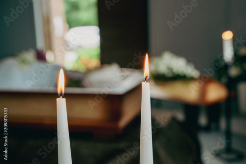 Burning funeral candles with blurred coffin in chapel background
