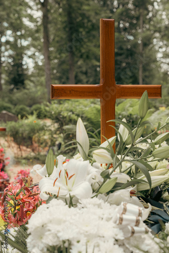 Картината върху платно Wooden Christian cross rising above white funeral flowers