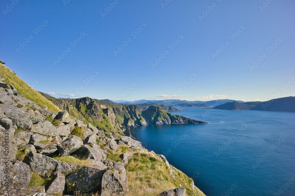 Fototapeta premium Breathtaking coastal landscape with steep rocky cliffs and deep blue ocean under a clear sky