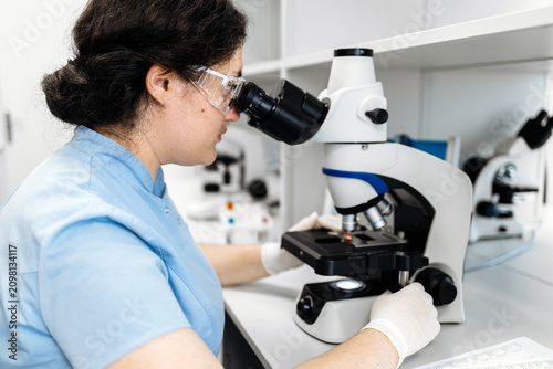 Fotografie Female scientist examining a sample under a microscope in a modern laboratory