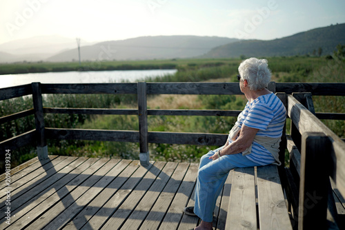 Healthy aging and senior lifestyle elderly woman sitting on a wooden bench enjoying nature and outdoor activity