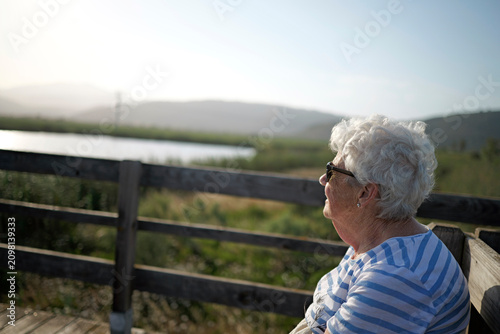 Healthy aging and senior lifestyle older woman enjoying nature outdoors with a serene expression and bright sunlight
