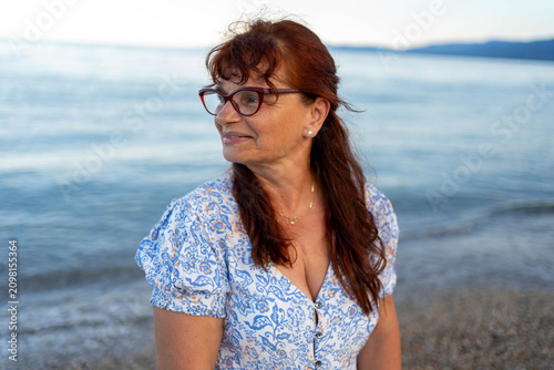 Foto Senior woman relaxing on the beach at sunset