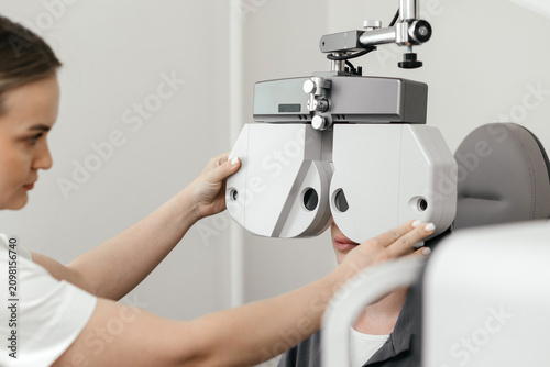 Eye doctor preparing a phoropter for comprehensive vision testing. Professional eye examination and refraction assessment in an ophthalmology clinic