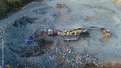 Espoo, Finland-April 14, 2025: Heavy machinery operating in a stone crushing plant, processing rocks and producing crushed stone in a building lot surrounded by forest in Finland during springtime