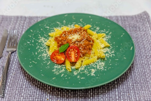 Obraz na płótnie Penne Pasta with Bolognese Sauce on Green Plate