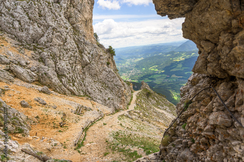 A scenic view of the Rax mountain trail in Austria showcases a winding path leading through rugged rock formations and earthy tones of brown and gray rocks contrasted with lush greenery
