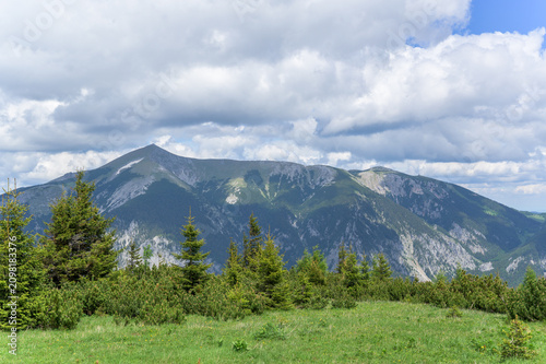 The stunning Rax Mountains display rugged peaks beneath a blue sky dotted with fluffy clouds
