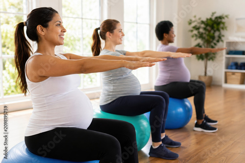 Pregnant women exercising on yoga balls. Diverse group of expectant mothers practicing prenatal fitness. Focus on health, exercise, and pregnancy wellness. Pregnancy and maternity image.