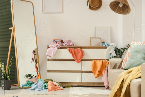 Foto Messy room with clothes scattered on a dresser and floor full-length mirror and