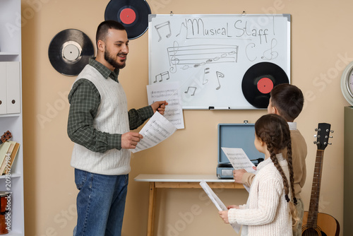 Konstfotografi Music teacher instructing children in a classroom with sheet music and a whitebo