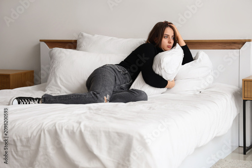 Sad young woman with pillow...