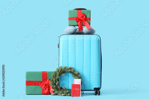 Suitcase with gift boxes and Christmas accessories on blue background