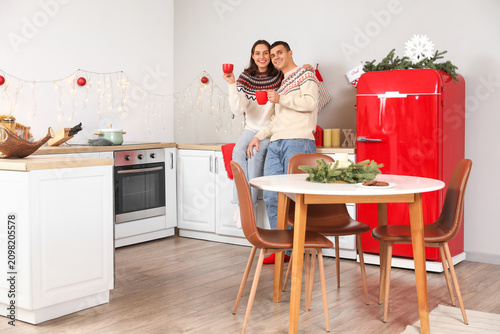 Young couple drinking hot cocoa in kitchen on Christmas eve