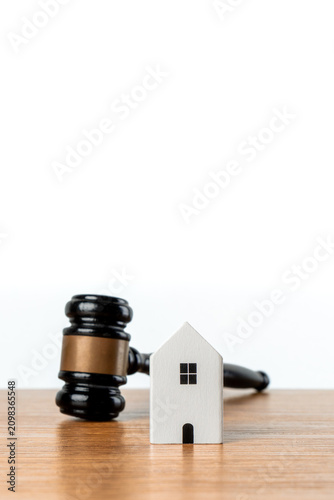Miniature white house and judge gavel. Real estate law, property foreclosure, eviction, mortgage disputes, divorce asset division, housing regulations, and property auctions concept.