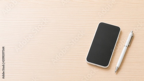 Minimal smartphone and white ballpoint pen on light wooden desk with copy space