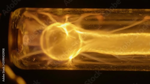 Glowing yellow neon tube light with warm illumination and detailed glass texture emitting bright glowing light closeup macro shot filament detail