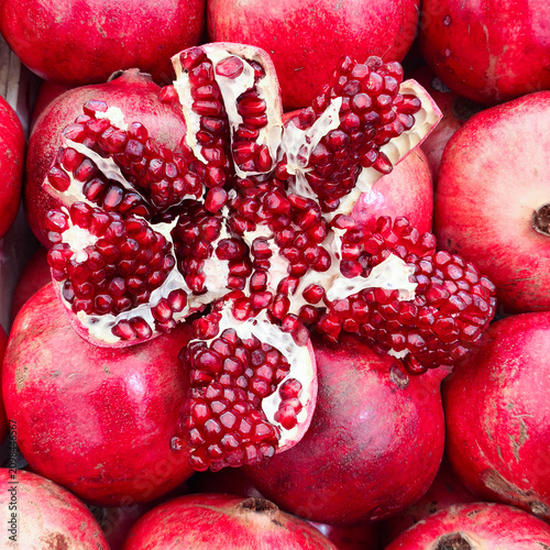 A close-up of a ripe and juicy Azerbaijani pomegranate. One of the fruits is half-peeled to reveal the ripe, ruby-colored seeds.