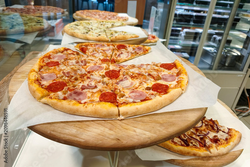 Pizza is a traditional Italian dish in the form of a round yeast tortilla baked with a filling on top. Pizza on a two-tier stand is for sale in the store window.