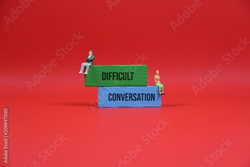 Bild auf Leinwand Difficult Conversation Concept With Miniature Couple Sitting on Stacked Blocks Against red Background