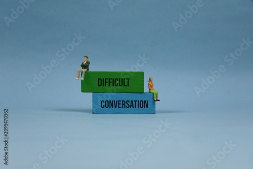 Difficult Conversation Concept With Miniature Couple Sitting on Stacked Blocks Against blue Background. illustrating relationship conflict and the need for dialogue or counseling.