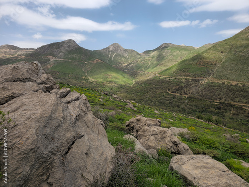 Large boulders rest on a rocky hillside overlooking a sweeping spring mountain valley with rugged green peaks.
📍 Hawraman Takht, Kurdistan, Iran 