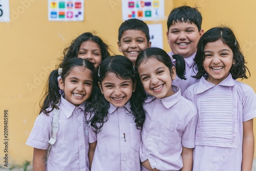 Group of cheerful indian school children in uniforms smiling and standing together for education marketing, childhood lifestyle advertising and k-12 school enrollments