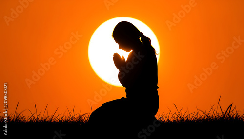 Silhouette of a woman kneeling and praying at sunset