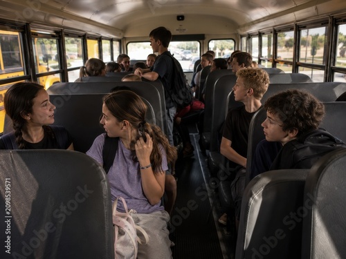 Diverse Group of High School Students Talking and Commuting to School Inside a Traditional Yellow School Bus