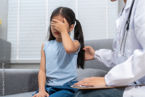Foto Young girl covering her face while a doctor examines her in a clinic, with a cli