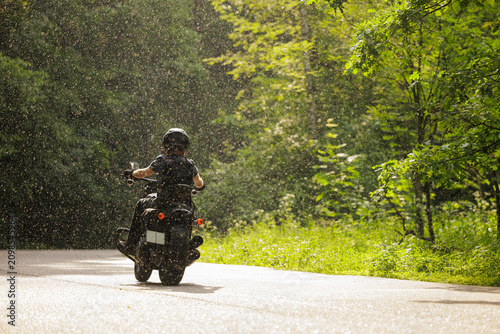 Fotografía Riding through a gentle rain in a lush forest on a summer day