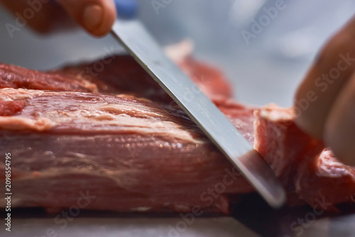 Cuadro en lienzo Butcher cleaning the meat from impurities