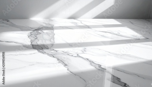 High angle view of a pristine white marble surface with elegant grey veining bathed in soft sunlight creating geometric shadow patterns.