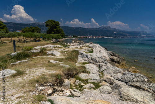 Bild auf Leinwand Panorama overlooking the city and monuments of Kastel in Croatia, pebbly beach D